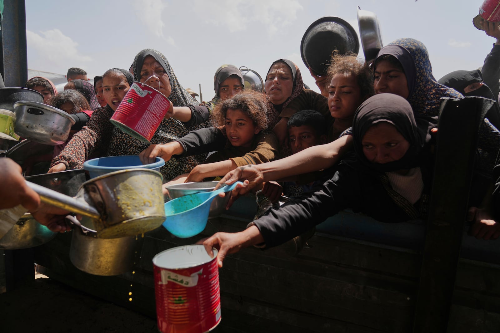 Palestinian children and women struggle to get donated food at a community kitchen in Khan Younis, Gaza Strip, Saturday, May 3, 2025. (AP Photo/Abdel Kareem Hana)
