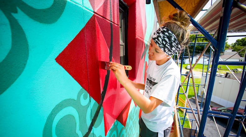 Ariel Williams works on a mural this past summer on Main Street in Hamilton. The StreetSpark program is accepting design proposals for three upcoming murals in Hamilton. GREG LYNCH/STAFF