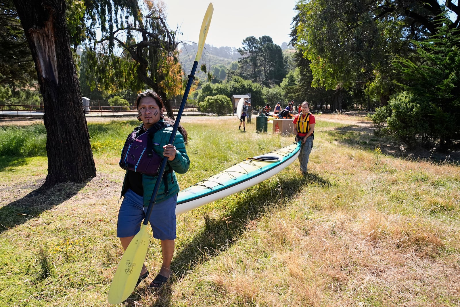 From left, Juan Bay, president of the Waorani people of Ecuador, and Isabella Zizi carry a kayak to the beach before entering the San Francisco Bay, Thursday, June 19, 2025, in Richmond, Calif. (AP Photo/Godofredo A. Vásquez)