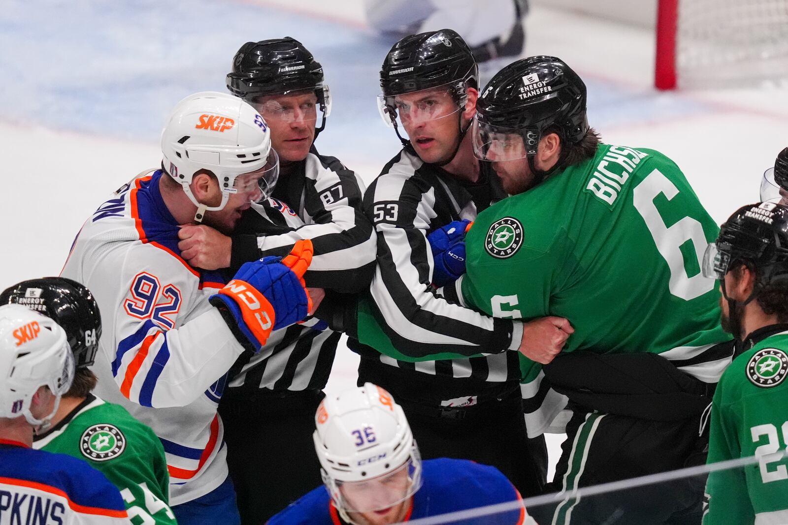Edmonton Oilers right wing Vasily Podkolzin (92) and Dallas Stars defenseman Lian Bichsel (6) have to be restrained by linesmen Devin Berg (87) and Bevan Mills (53) during the third period in Game 2 of the Western Conference finals in the NHL hockey Stanley Cup playoffs, Friday, May 23, 2025, in Dallas. (AP Photo/LM Otero)