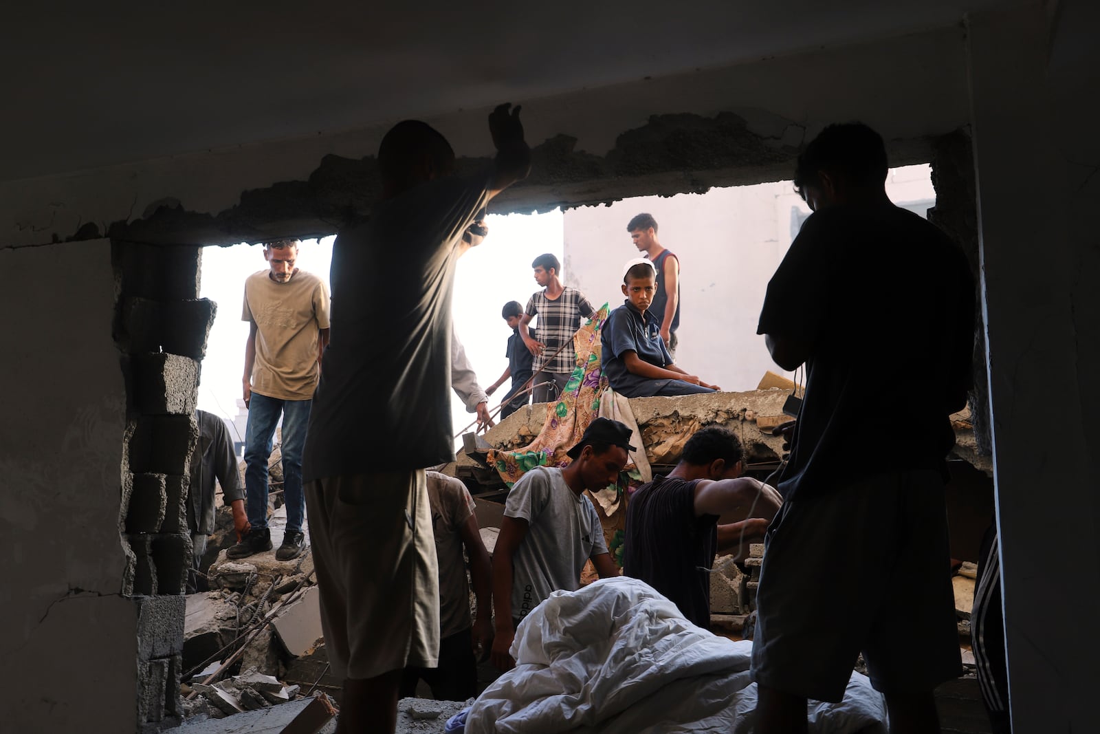 Palestinians inspect the site struck by an Israeli bombardment in Muwasi, Khan Younis, Gaza Strip, Monday, July 28, 2025. (AP Photo/Mariam Dagga)