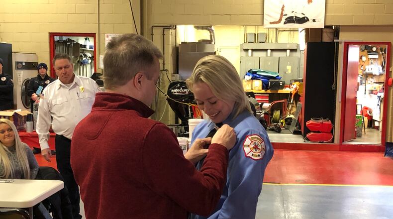Celine Schank, 24, a 2015 Lakota West High School graduate, is pinned by her father, Thomas, Friday during a ceremony at Fire Headquarters. Fire Chief Paul Lolli looks on. RICK McCRABB/STAFF