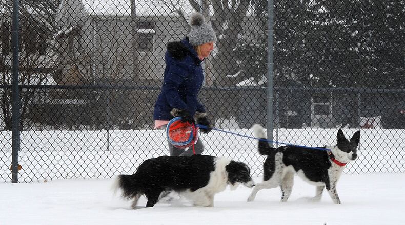 A woman walks her dogs near Shawnee Park in Xenia, on a snowy Wednesday, Feb. 10, 2021. Cold temperatures are expected this weekend, meaning recent snowfall will remain on the ground for an extended period of time. MARSHALL GORBY\STAFF
