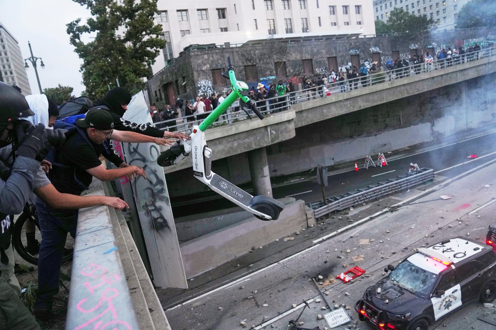 A protester throws a scooter at a police vehical near the metropolitan detention center of downtown Los Angeles, Sunday, June 8, 2025, following last night's immigration raid protest. (AP Photo/Jae C. Hong)