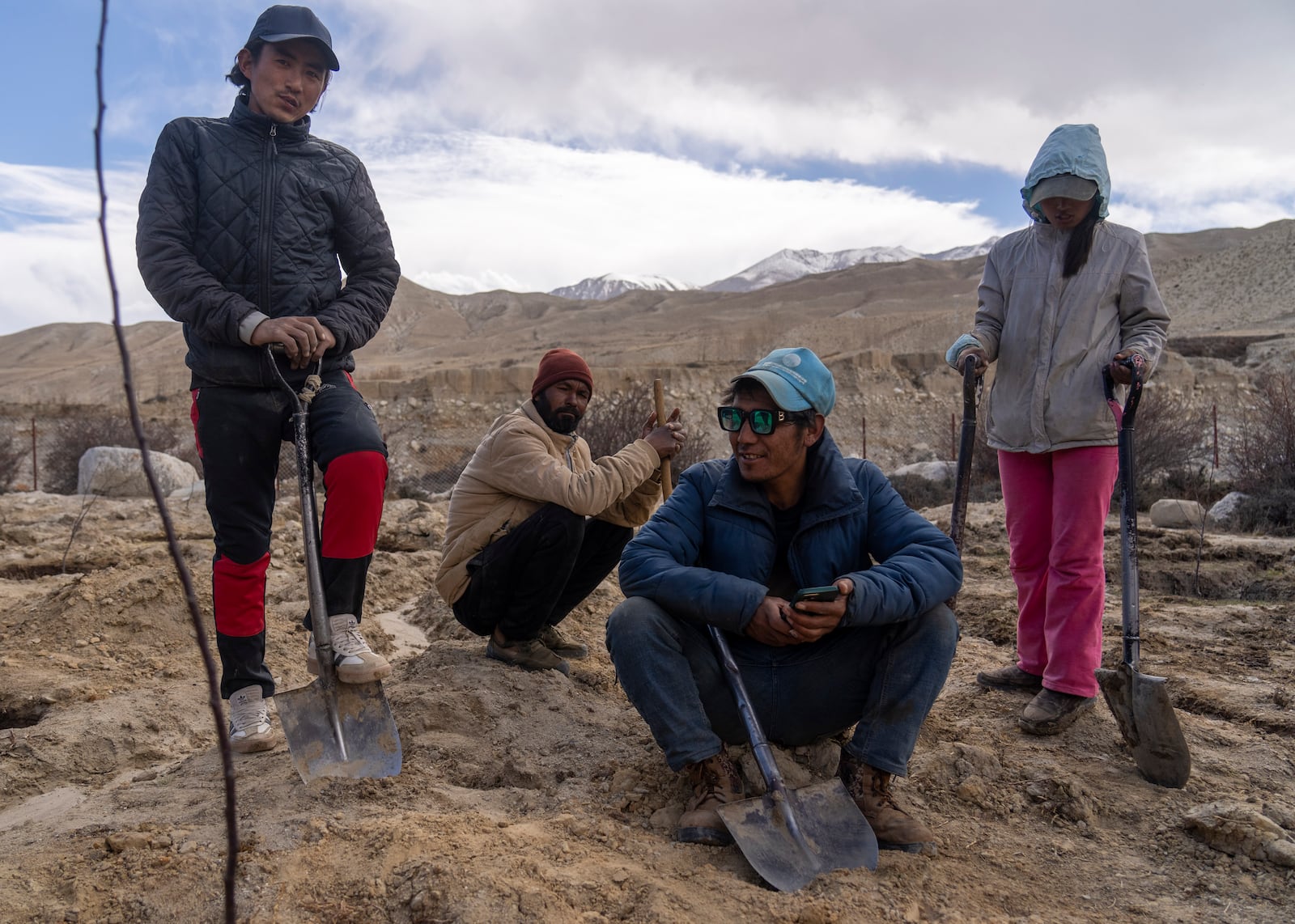 Villagers take a break while working in a field at the newly relocated settlement of the abandoned Samjung village in the Mustang region, 462 kilometers (288 miles) west of Kathmandu, Nepal, Friday, April 18, 2025. (AP Photo/Niranjan Shrestha)