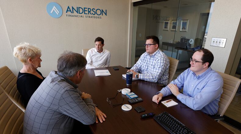 Anderson Financial Strategies President and Chief Wealth Strategist Shon Anderson (center), with Matthew Peck and Collin Lyon (right) talk with a couple in the firm's Dayton office Monday, Dec. 23, 2024, about being financially prepared for retirement. MARSHALL GORBY/STAFF