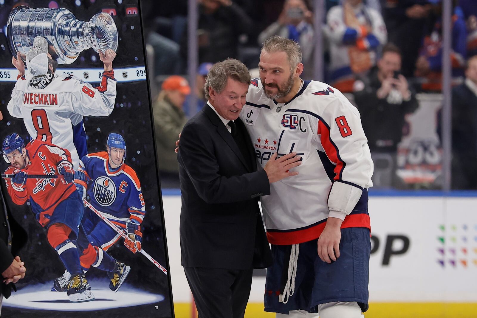Washington Capitals left wing Alex Ovechkin, right, is greeted by Wayne Gretzky during a ceremony after he scored his 895th career goal during the second period of an NHL hockey game against New York Islanders in Elmont, N.Y., Sunday, April 6, 2025. (AP Photo/Adam Hunger)