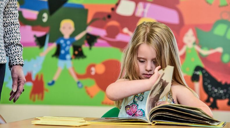 Natalie Stuck, 5, reads a book in the pre-k class at the daycare at First Baptist Church on Riverview Ave. in Middletown Thursday, May 7, 2020. The daycare, which is one of the temporary pandemic child care providers, would normally have over a hundred kids but is now allowed only thirty-six children divided into six rooms. NICK GRAHAM / STAFF
