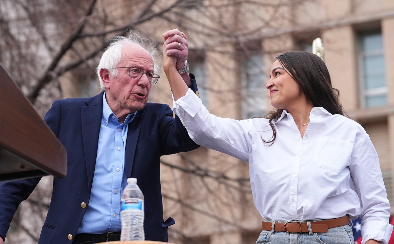 FILE _ Sen. Bernie Sanders, I-Vt., left, greets Rep. Alexandria Ocasio-Cortez, D-N.Y., as they speak during a stop of their "Fighting Oligarchy" tour at Civic Center Park, March 21, 2025, in Denver. (AP Photo/David Zalubowski, File)