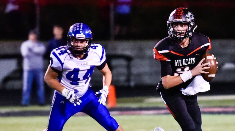 Franklin quarterback Braden Woods looks for an open man as Brookville’s Alex Cherry pursues Thursday night at Atrium Stadium in Franklin. NICK GRAHAM/STAFF