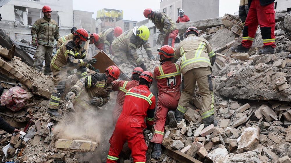Rescue workers search for survivors in the rubble after a strike in southern Tehran, Iran, Friday, March 13, 2026. (AP Photo/Sajjad Safari)