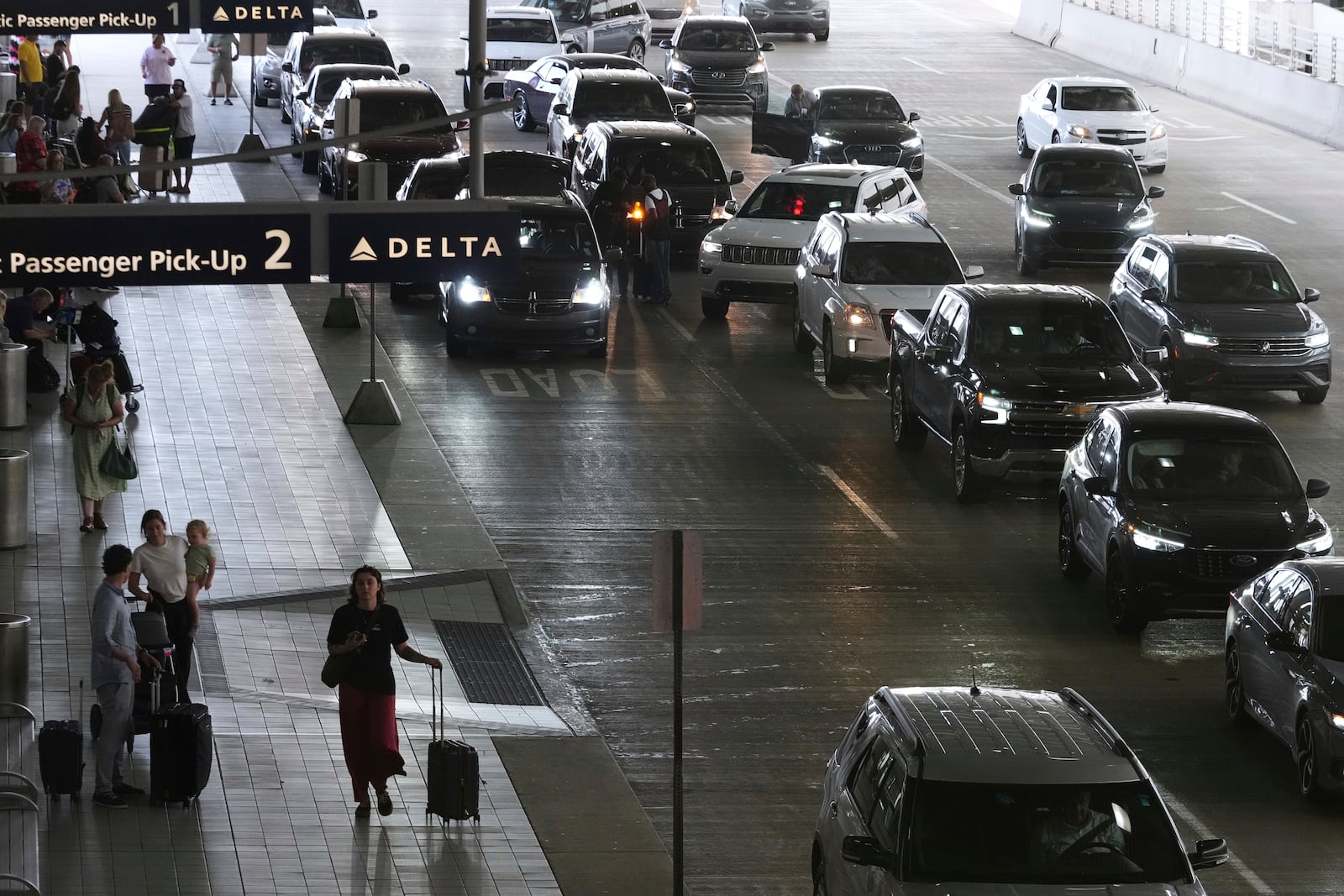 Travelers arrive and depart a terminal at Detroit Metropolitan Airport in Romulus, Mich., Thursday, July 3, 2025. (AP Photo/Paul Sancya)