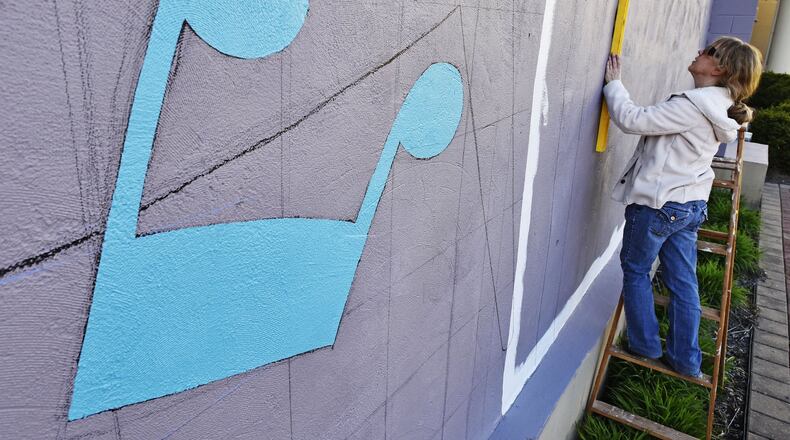 In this 2016 file photo, Rhonda Gardner works on a mural being on the side of a building facing Governor’s Square along Central Avenue and Broad Street in Middletown. Gardner died in July 2016 and some of her unfinished work was completed by area artists and turned into an exhibit at the Pendleton Art Center. NICK GRAHAM/FILE