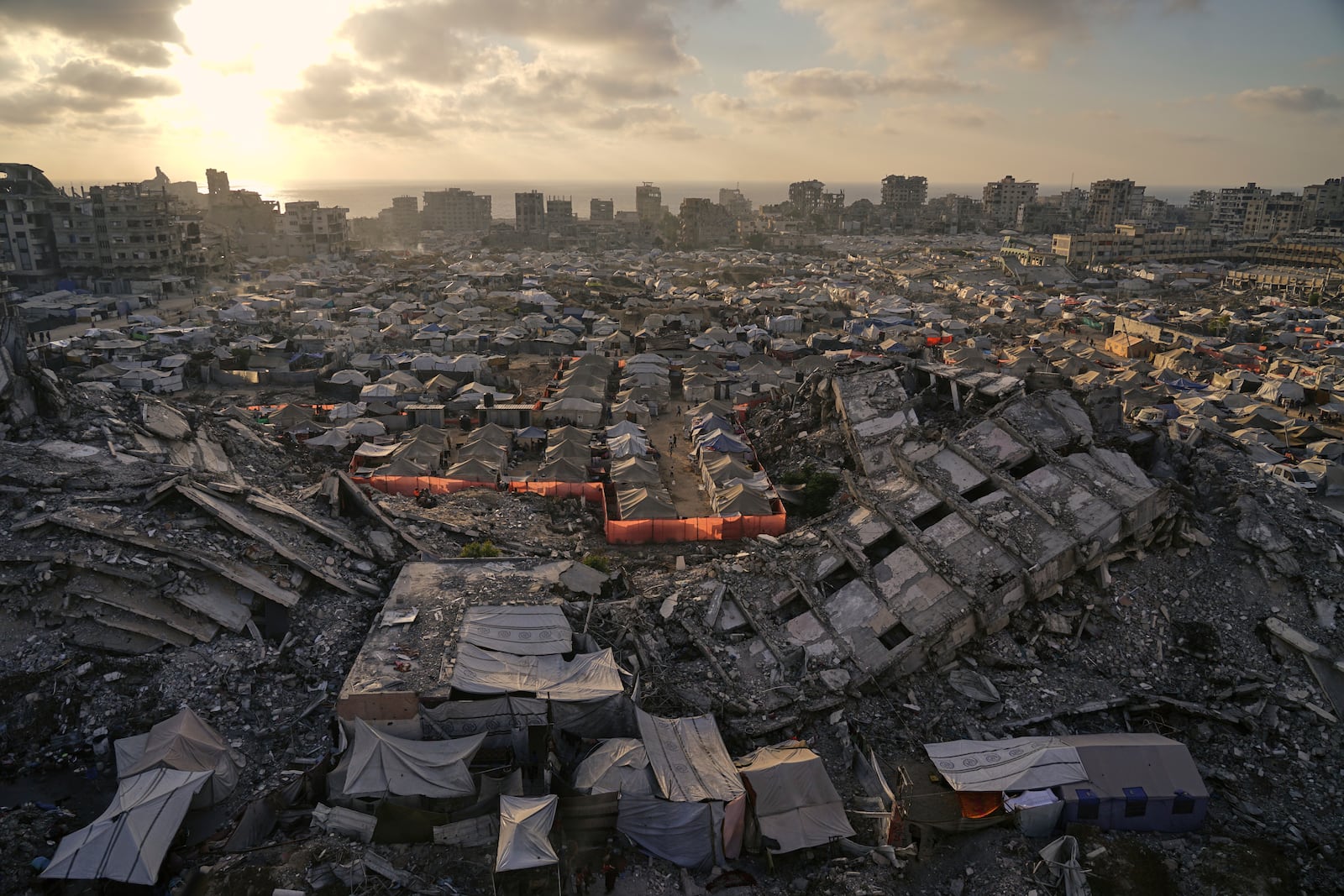 A tent camp for displaced Palestinians stretches among the ruins of buildings destroyed by Israeli bombardments in west of Gaza City, Saturday, June 21, 2025. (AP Photo/Jehad Alshrafi)