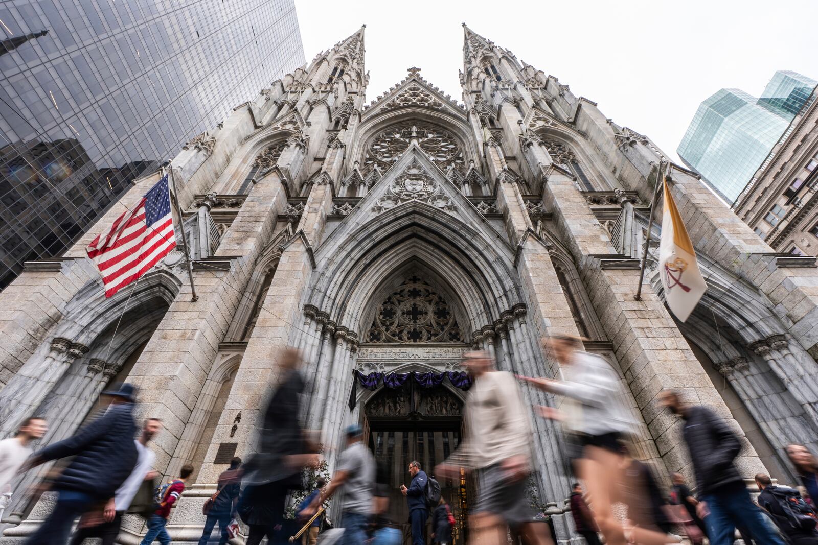 People walk past St. Patrick's Cathedral as dark drapes hang over the doorway before a memorial mass for the late Pope Francis, Saturday, April 26, 2025, in New York. (AP Photo/Julia Demaree Nikhinson)