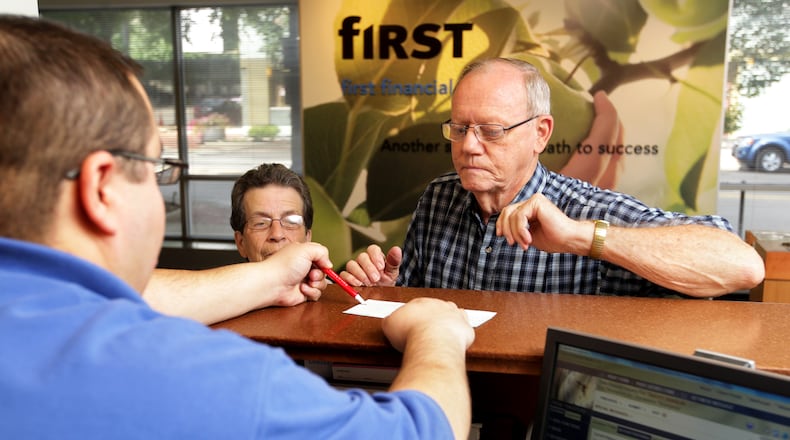 Gregory Silva (left) helps Vonda and Ray Thompson close a certificate of deposit at First Financial Bank on High Street in downtown Hamilton in 2013. First Financial was founded in Hamilton more than 150 years ago. NICK DAGGY / STAFF