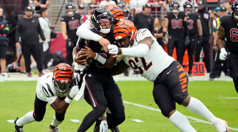 Arizona Cardinals quarterback Joshua Dobbs center, is sacked by Cincinnati Bengals defensive end Trey Hendrickson, rear, and Cincinnati Bengals defensive tackle BJ Hill (92) during an NFL football game, Sunday, Oct. 8, 2023, in Glendale, Ariz. (AP Photo/Rick Scuteri)