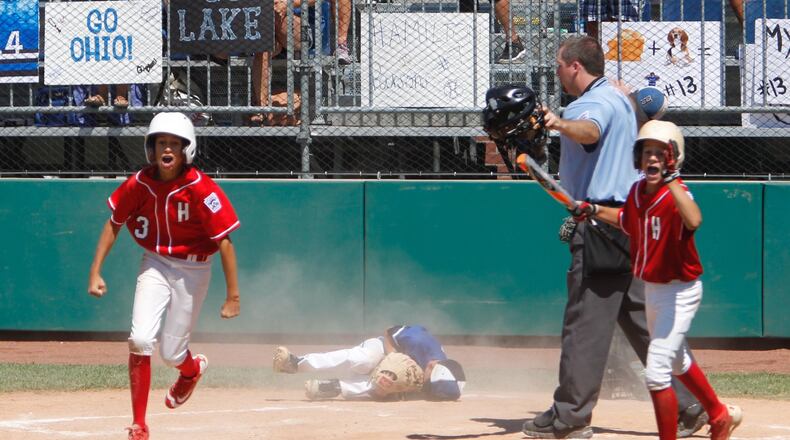 Hinsdale (Ill.) runner Emerson Eck (3) celebrates scoring the winning run on a wild pitch in the bottom of the sixth inning Wednesday as Hamilton West Side suffered a 5-4 defeat in the Little League Great Lakes Regional at Grand Park Sports Campus in Westfield, Ind. That’s West Side pitcher Ethan Mueller on the ground after trying to make the play at the plate. GREG LYNCH/STAFF