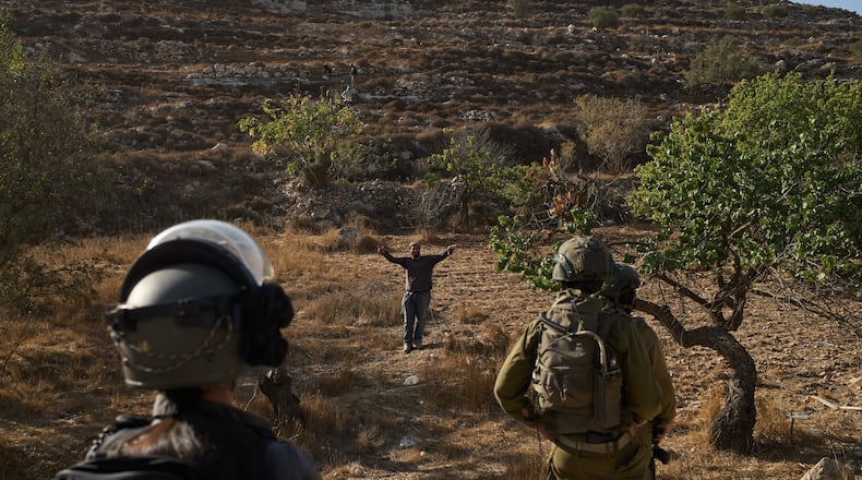 An Israeli settler gestures as Israeli soldiers block access for Palestinians to an area for harvesting olives in the West Bank village of Sa'ir, near Hebron, Thursday, Oct. 23, 2025. (AP Photo/Leo Correa)