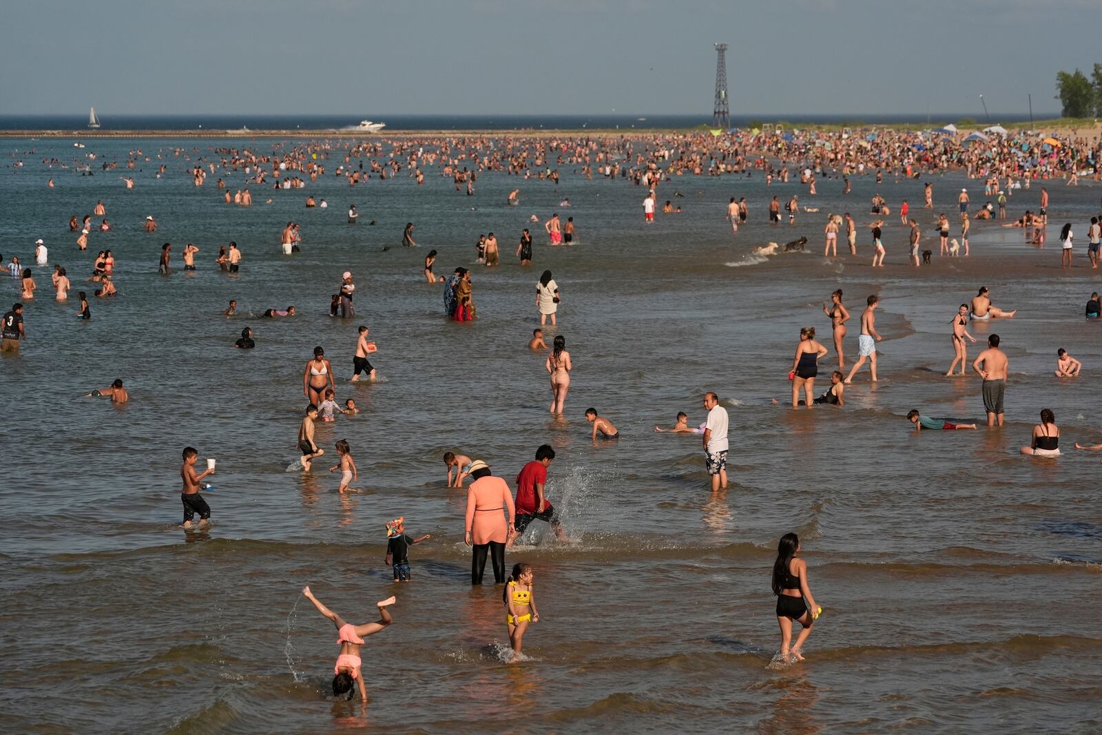 Beach goers crowd a public beach on the Lake Michigan shore, Sunday, June 22, 2025, in Chicago. (AP Photo/Kiichiro Sato)