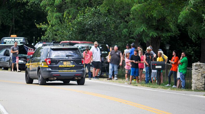 A Butler County Sheriff’s Deputy drives by a group of people on Elk Creek Road in Madison Township gathering to support the owner of a German Shepherd named Ruger that had to be put down from injuries sustained after a neighbor allegedly hit the dog with a baseball bat. NICK GRAHAM/STAFF