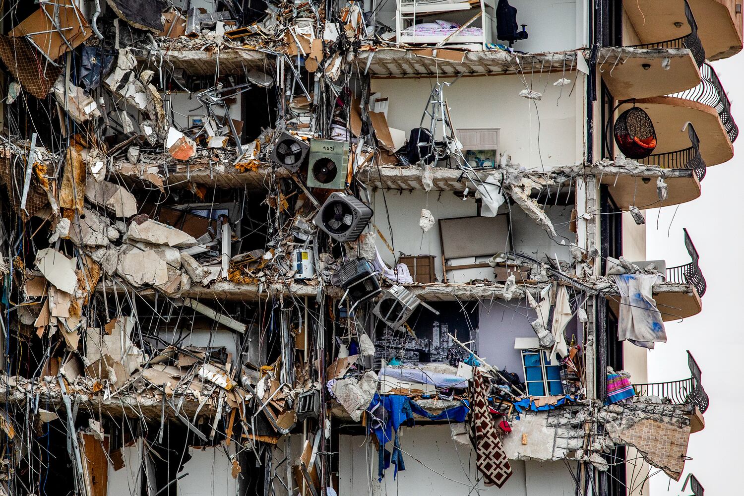 Air conditioning units, and personal belonging hang from a high-rise residential building that is partially collapsed in Surfside, Fla., Thursday, June 24, 2021. (Scott McIntyre/The New York Times)