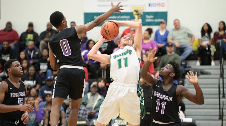 New Miami’s Nate Hobbs (11) drives between Gamble Montessori’s Kaden Warner (0) and Jeremi Cauley (11) during Saturday night’s Division IV district semifinal at Taylor. New Miami won 48-47. PHOTO BY KRAE/WWW.KRAEPHOTOGRAPHY.COM