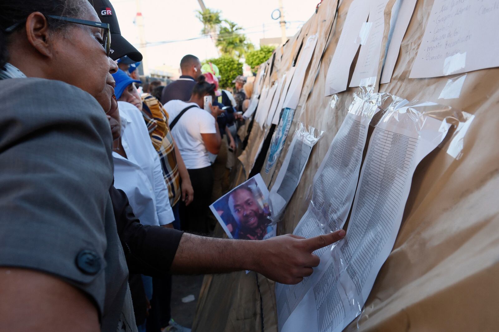 People searching for their missing relatives peruse a list of names outside the Jet Set nightclub after its roof collapsed during a merengue concert in Santo Domingo, Dominican Republic, Tuesday, April 8, 2025. (AP Photo/Ricardo Hernandez)