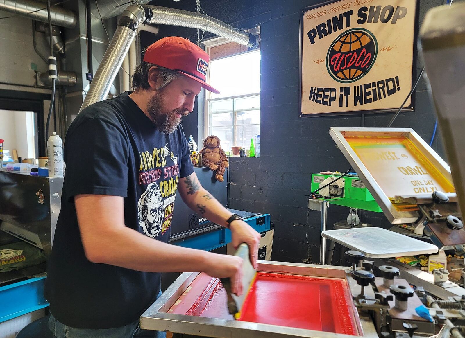 Justin Carder, with Unsung Salvage Design Company in Hamilton, prints a special edition shirt for Midwest Record Store Crawl Saturday, March 23, 2024. Eighteen record shops from northern Kentucky to Dayton participated including Unsung Salvage, Lester's Rock n Roll Shop in Middletown and Three Feather Records in Fairfield. NICK GRAHAM/STAFF