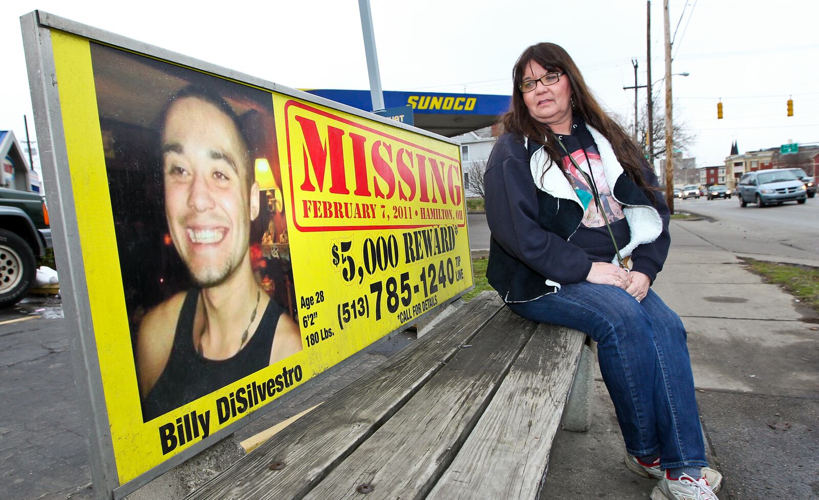 Debbie Winkler Estes sits on a bench with information about her son Billy DiSilvestro, who has been missing since 2011. Estes has become a supporter to many other local families who have loved ones that are missing. STAFF/FILE PHOTO