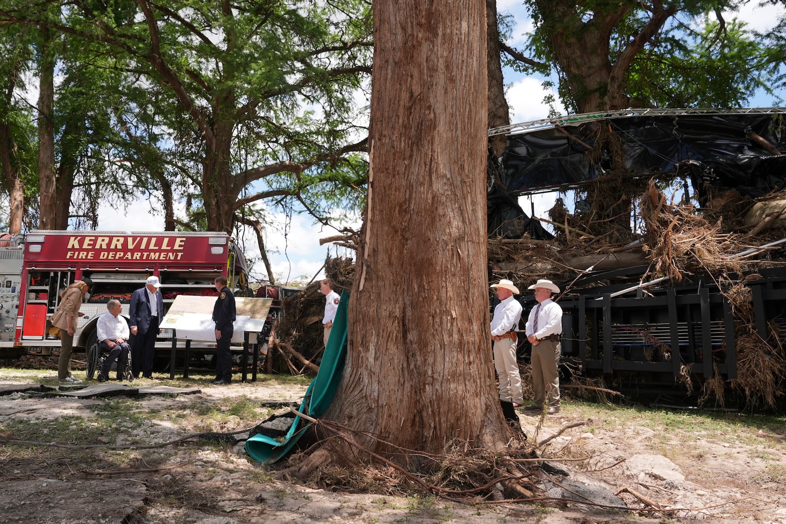 First lady Melania Trump, from left, Texas Gov. Greg Abbott and President Donald Trump are briefed on flood damage in Kerrville, Texas, Friday, July 11, 2025. (AP Photo/Jacquelyn Martin)