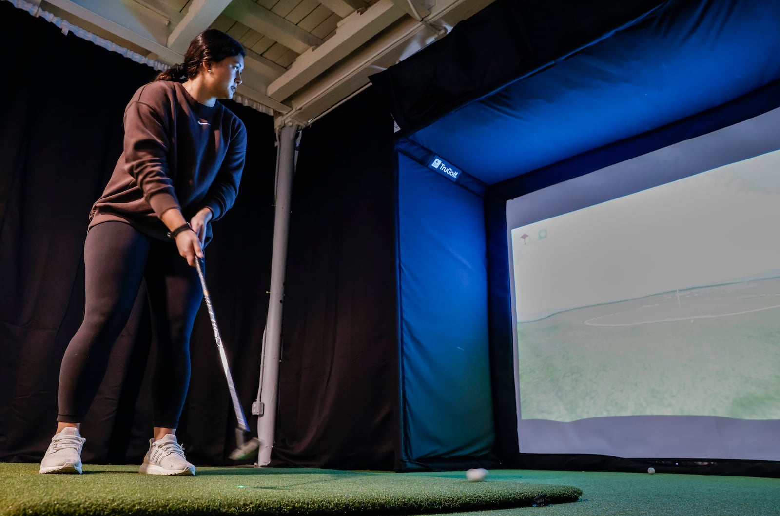 Nyah Namisnak shows how the simulator works at Inside 18 golf and sports simulator Thursday, Jan. 15, 2026 at Spooky Nook Sports Champion Mill in Hamilton.  The new indoor sports simulator facility is mostly used for golf, but it also features baseball, soccer, football and other sports. NICK GRAHAM/STAFF