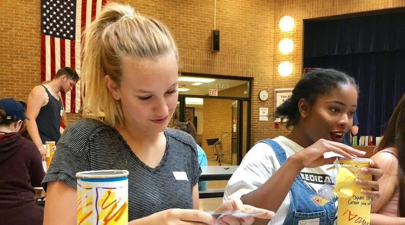 Lakota West High School graduating seniors Amy Whitaker and Camdyn Stradford open time capsules they created when they were sixth-graders at Adena Elementary. The event is the creation of Adena teacher Lori Combs. More than 150 students returned to their old school this year to open the containers they left for their future selves. MICHAEL D. CLARK/STAFF