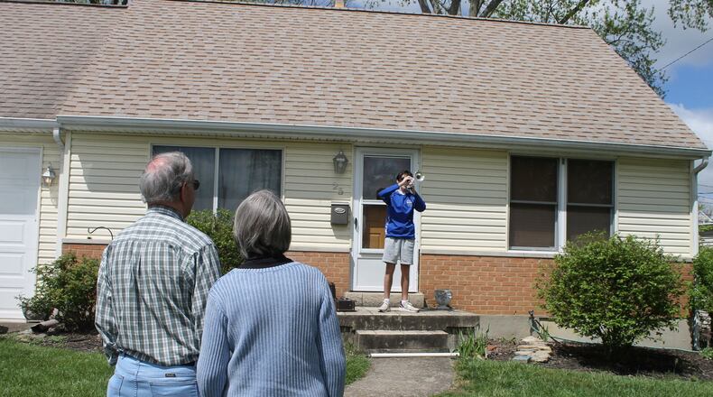 Hamilton Schools 9th grader Steven Colwell lifted his horn and joined hundreds of other school band members Friday who stepped in front of their homes at noon and played the Hamilton High School “Big Blue Chant” fight song to honor graduating seniors. In another city community, Hamilton junior Ezra Simmons played the song on his flute for his family and neighbors. PROVIDED