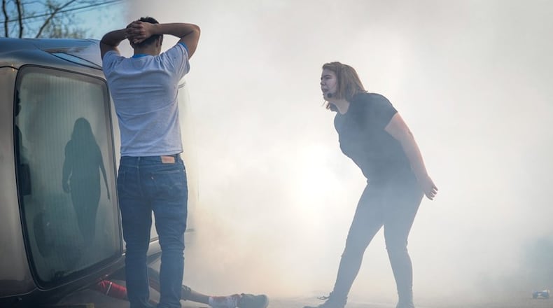 Hamilton High School senior Olivia Mueller, right, plays the role of hysterical friend as she yells at Alex Oseguera during a mock crash presented by The Greater Hamilton Safety Council to share with students the dangers of distracted driving April 12 at Hamilton High School. FILE