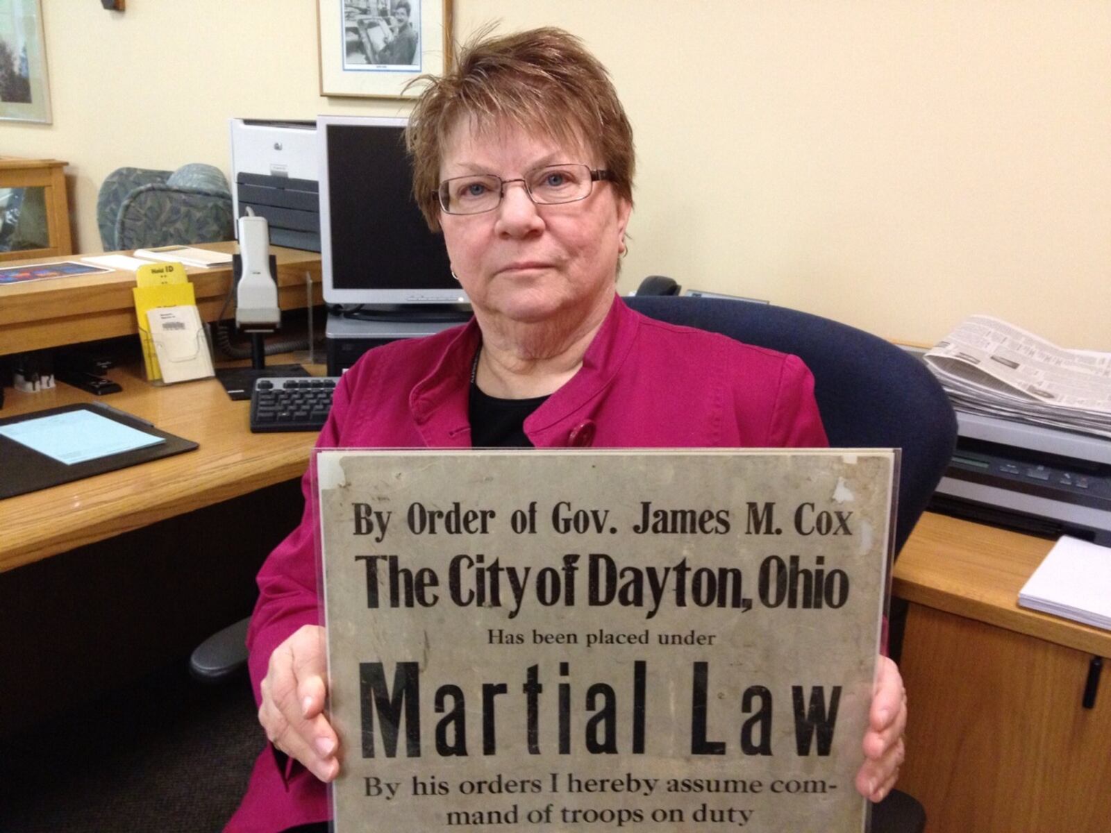 Nancy Horlacher, local history specialist for Dayton Metro Library, holds a poster that declared Martial Law during the flood crisis.