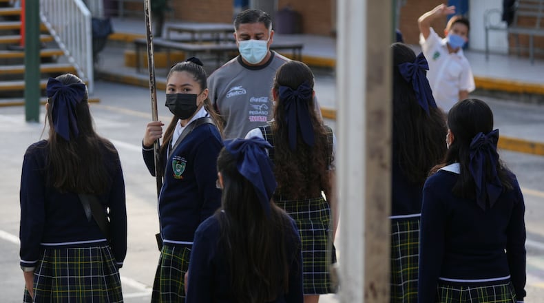 Public school students and teachers wear mandatory face masks amid a measles outbreak, during a ceremony at their school in Guadalajara, Mexico, Thursday, Feb. 5, 2026. (AP Photo/Fernando Llano)