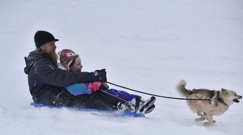 Jason Bender and Breanna Bender, 8, sled IN the snow with their dog, Lucy, Tuesday, February 9, 2021 at Harbin Park in Fairfield. NICK GRAHAM  / STAFF