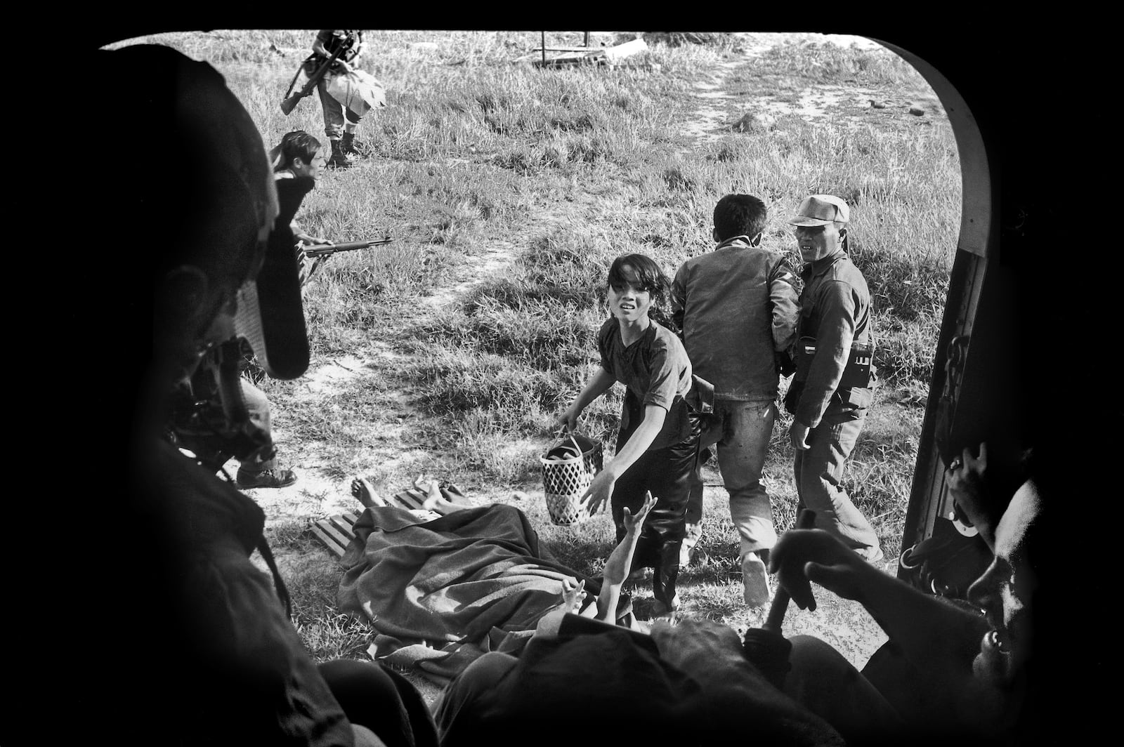 FILE- As her wounded husband raises his arm, a Vietnamese woman begs to be taken aboard a U.S. evacuation helicopter so they can escape a Viet Cong attack in Ba Gia, July 1965. The couple was left behind. (AP Photo/Eddie Adams, File)