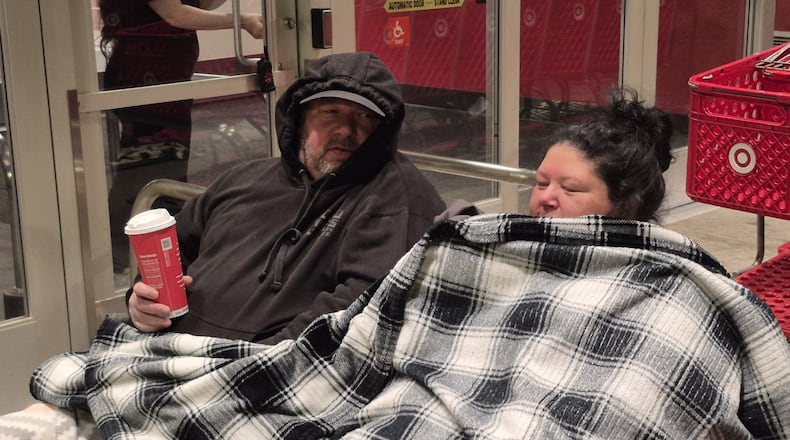 John and Virginia Nesbit huddle beneath a blanket while waiting for the Beavercreek Target store to open on Black Friday. Some retailers used giveaways to drive traffic to their stores for the Thanksgiving shopping weekend. MICHAEL KURTZ / STAFF