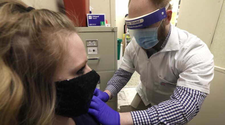 Andrew Hoffman, a pharmacist at Discount Drug Mart in Enon, early in the flu season gave Jennifer Boswell a flu shot at the pharmacy. BILL LACKEY/STAFF