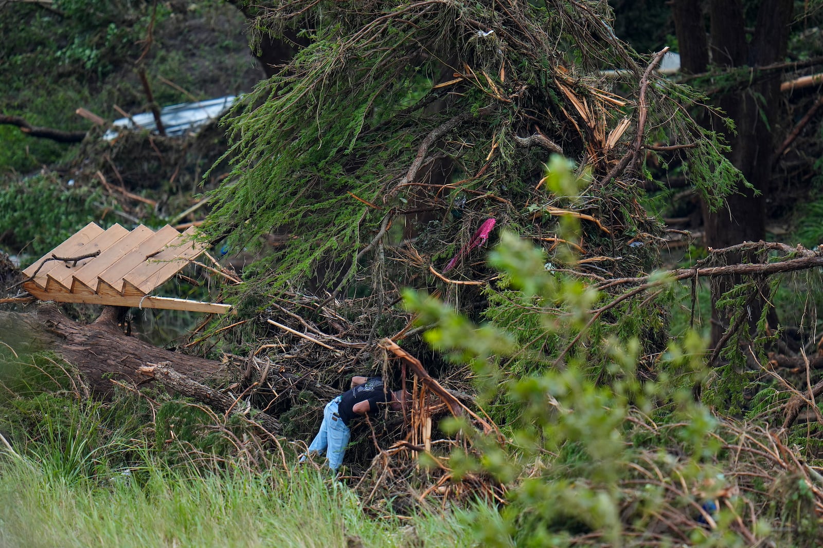 A person searches among debris near the banks of the Guadalupe River after a flash flood swept through the area Saturday, July 5, 2025, in Hunt, Texas. (AP Photo/Julio Cortez)