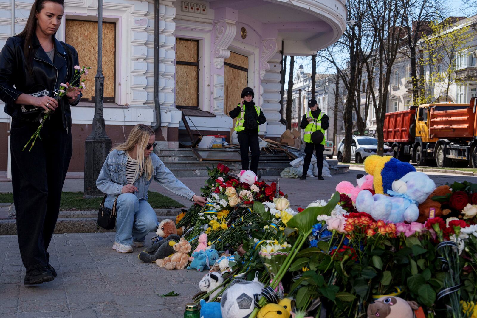 Women put flowers on a site of a Russian missile strike in Sumy, Ukraine, April 15, 2025. (AP Photo/Evgeniy Maloletka)