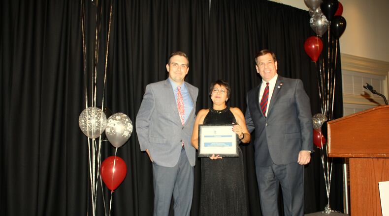 Joe Hinson (right), president and CEO of the West Chester-Liberty Chamber Alliance, presents former Reach Out Lakota CEO/Executive Director Lourdes Ward (center) with a plaque denoting her 25 years of service to the organization and the West Chester/Liberty Township community during the 6th Annual Celebrity Waiter Dinner in 2017. J. Peyton Gravely, Reach Out Lakota’s current CEO/executive director is pictured on the left. CONTRIBUTED