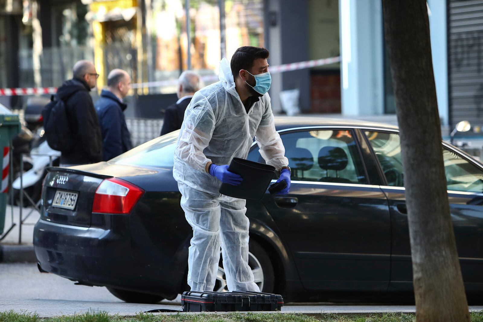 A Greek police forensic expert searches for evidence at the area where a 38-year-old woman was killed early Saturday when a bomb she was carrying exploded in her hands outside a bank branch, local police said, in Thessaloniki, northern Greece, May 3, 2025. (AP Photo/Giannis Papanikos)