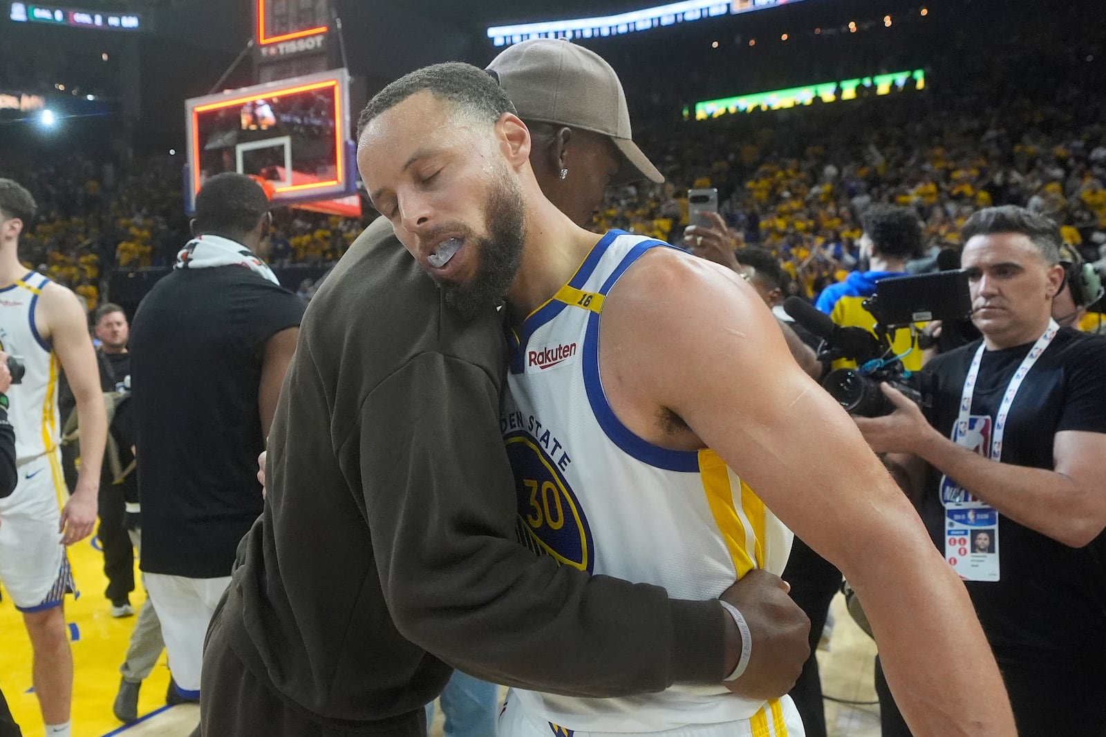 Golden State Warriors guard Stephen Curry, foreground, celebrates with injured forward Jimmy Butler III after Game 3 of an NBA basketball first-round playoff series against the Houston Rockets in San Francisco, Saturday, April 26, 2025. (AP Photo/Jeff Chiu)