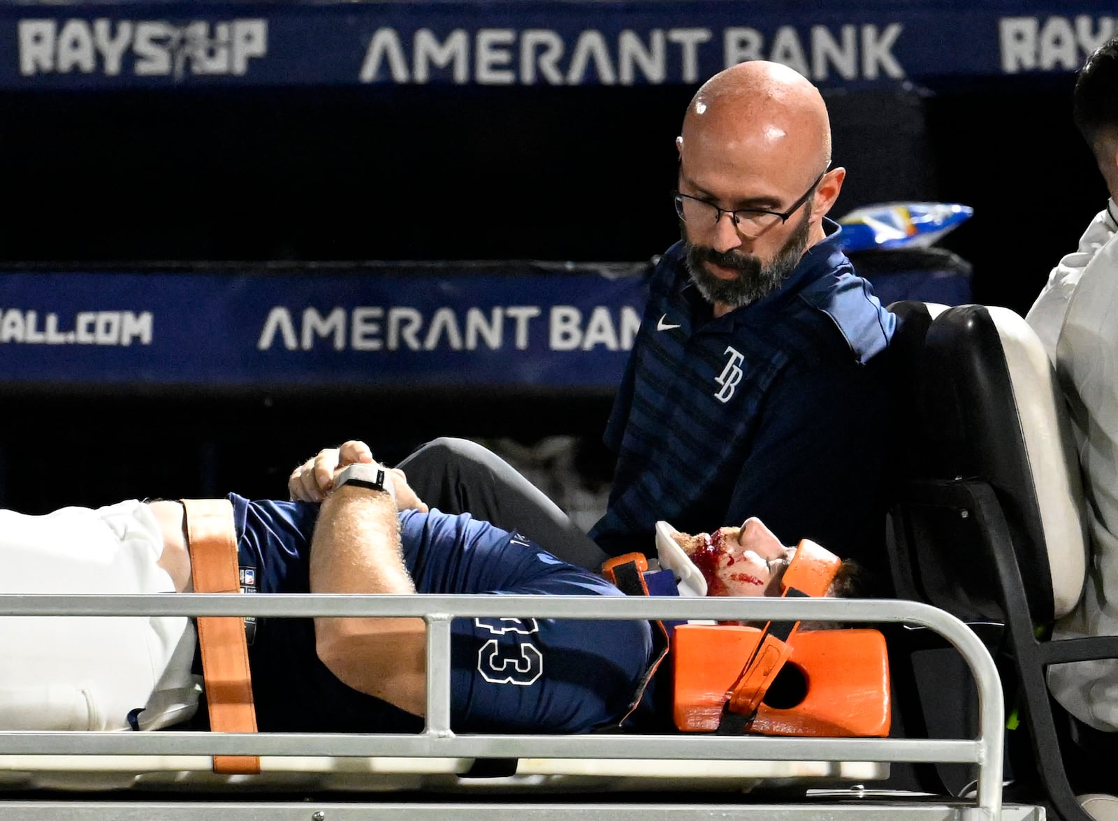Tampa Bay Rays' Hunter Bigge is taken off the field after being hit by a foul ball while in the dugout during the seventh inning of a baseball game against the Baltimore Orioles, Thursday, June 19, 2025, in Tampa, Fla. (AP Photo/Jason Behnken)
