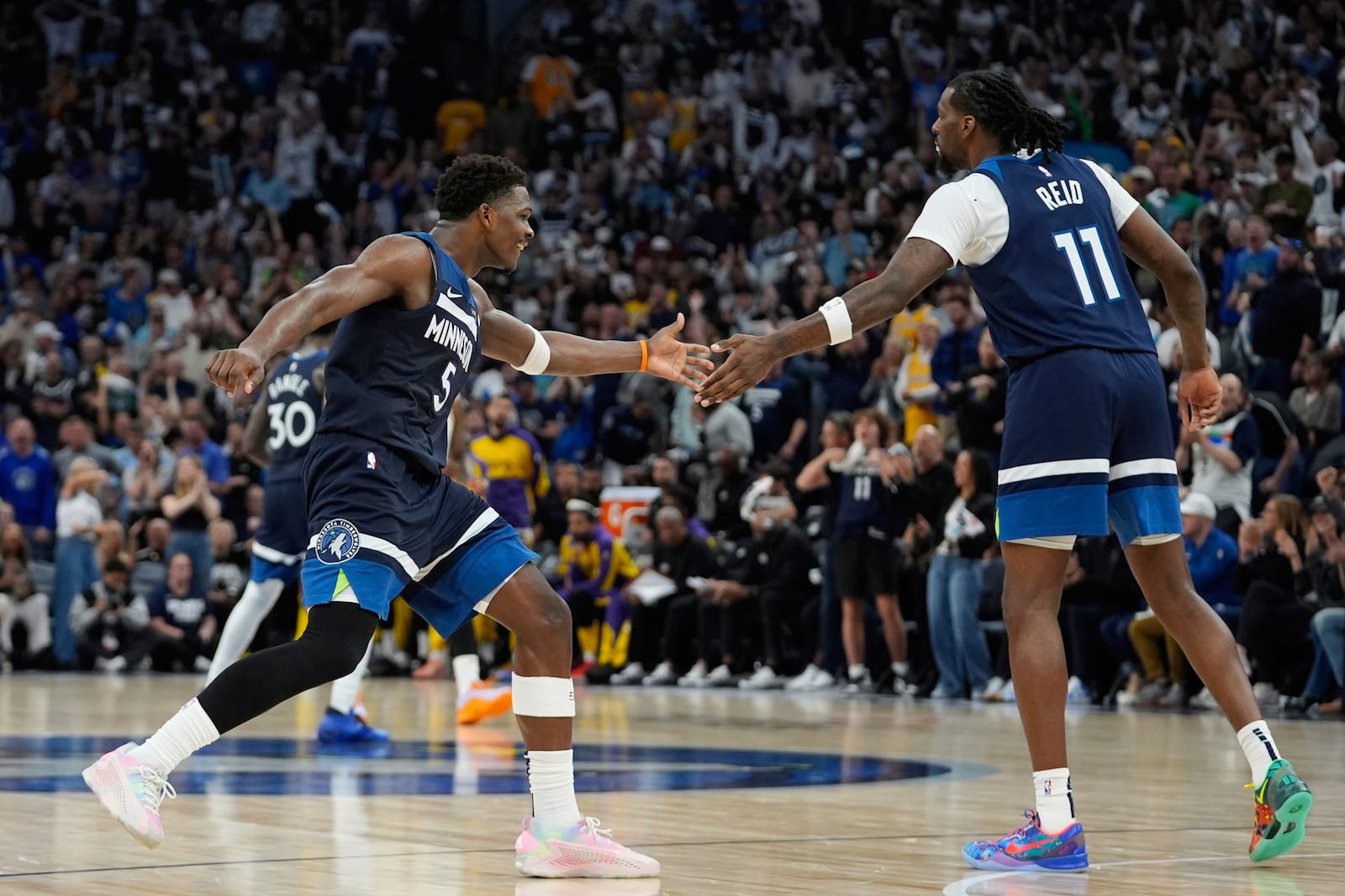 Minnesota Timberwolves center Naz Reid (11) celebrates with guard Anthony Edwards (5) after making a 3-point shot during the second half of Game 4 of an NBA basketball first-round playoff series against the Los Angeles Lakers, Sunday, April 27, 2025, in Minneapolis. (AP Photo/Abbie Parr)