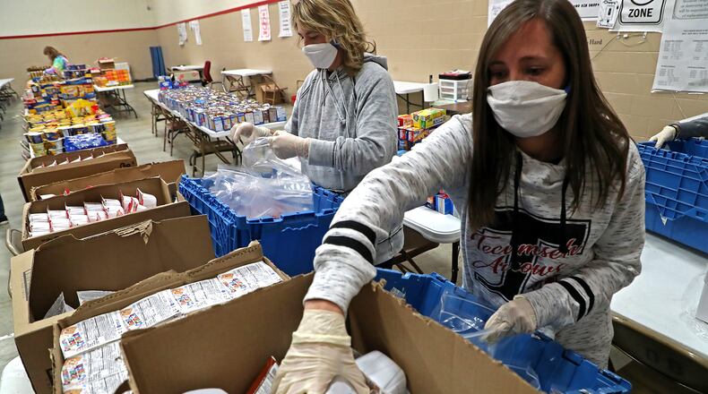 Staff and volunteers at Tecumseh High School, including Natalie Jackson, right, spent the afternoon filling food bags for students with food the community donated. BILL LACKEY/STAFF
