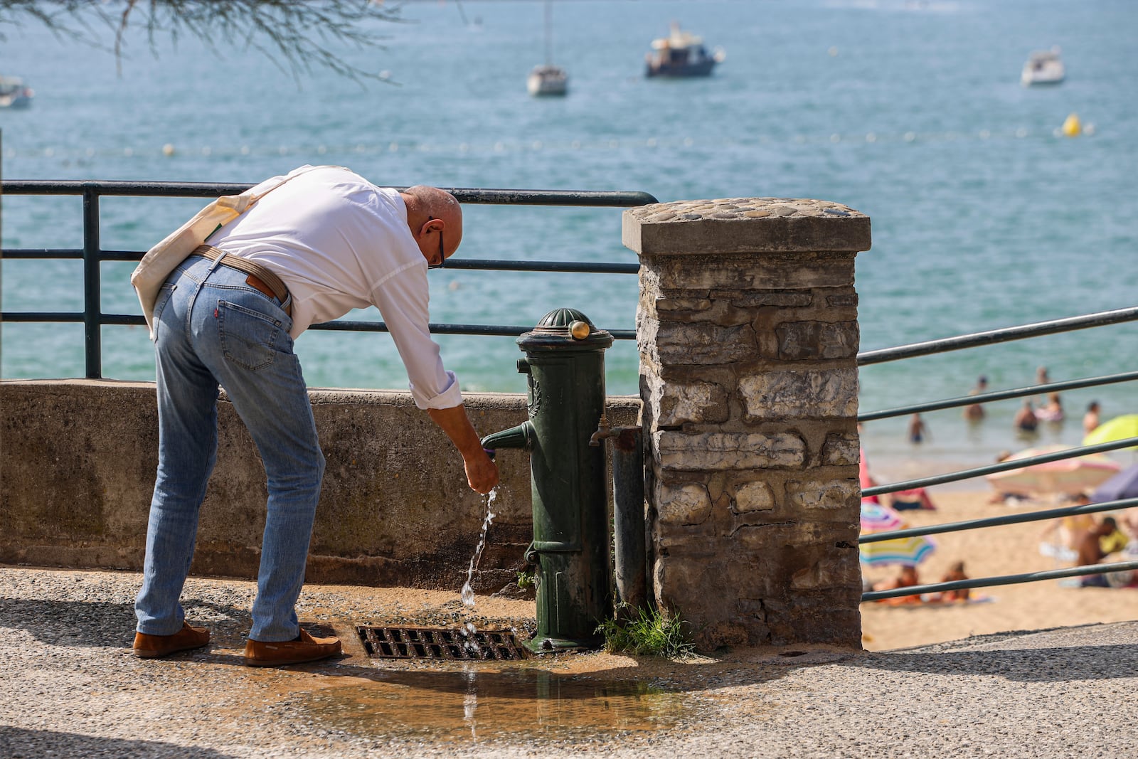 A man refreshes his hands Monday, June 30, 2025 on the seafront in Saint-Jean-de-Luz, southwestern France. (AP Photo/Nicolas Mollo)